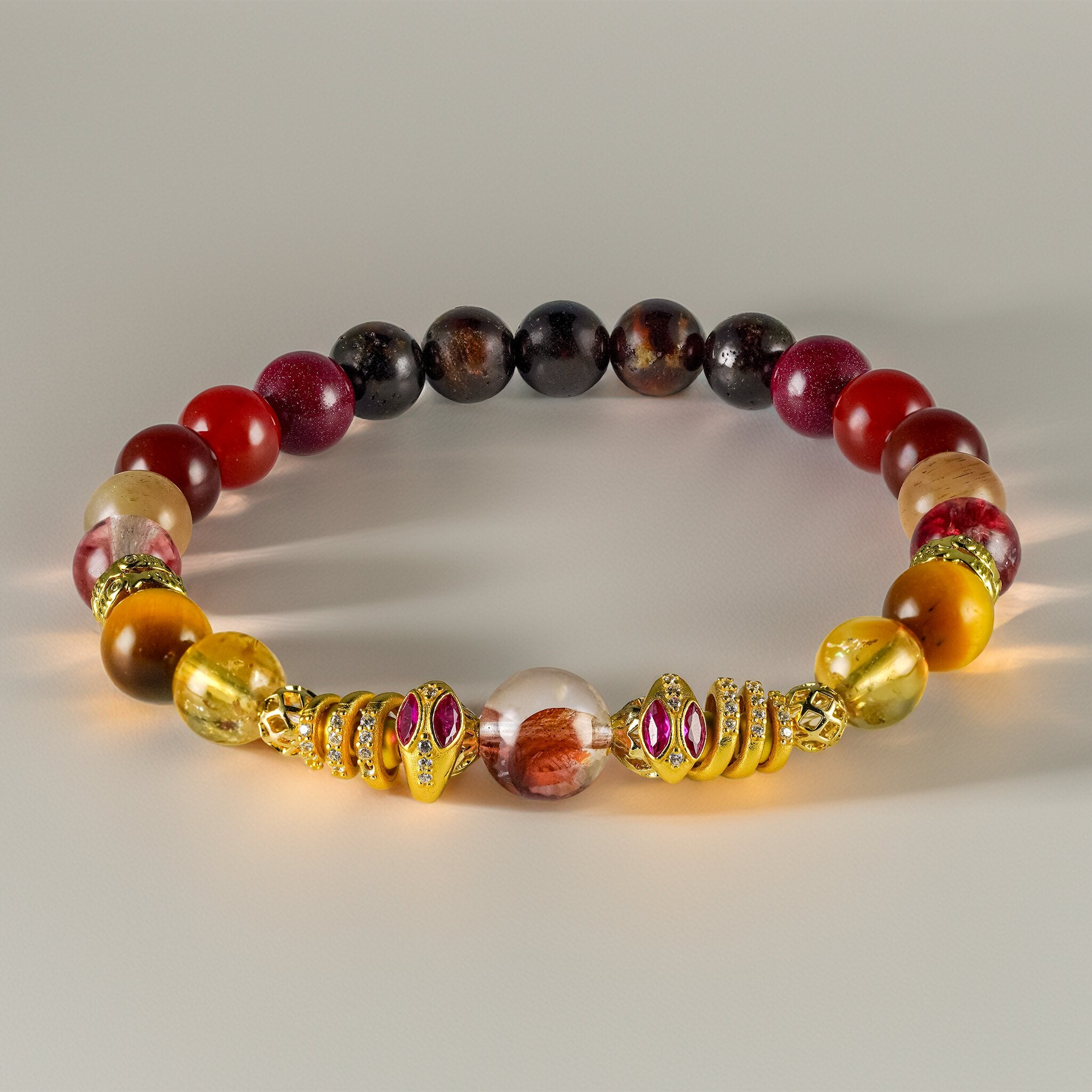 Secret Guardians Royal Serpents Collection Pyra bracelet by XOIAX with Collector-Grade Fire Quartz and ruby-eyed 24k gold serpent charms, a feng shui bracelet for shielding negative energy
